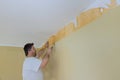 Man hand tear off old light wallpaper from wall preparing for home repair work removing wallpaper with a spatula Royalty Free Stock Photo