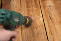 Man processes wooden boards with power tool. Flap wheel in the cam of the electric drill chuck. Tool for woodworking, sanding,