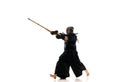 Man, professional kendo athlete in motion, in uniform training with bamboo sword, shinai against white studio background Royalty Free Stock Photo