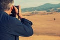 Man professional photographer with digital camera taking photos of fields and moutains, Italy