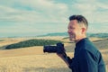 Man professional photographer with digital camera walking in tuscany fields and taking photos. Photo Camera in male hands over Royalty Free Stock Photo