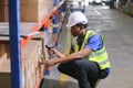 Man professional worker wearing safety uniform and hard hat worker scanning box inspect product on shelves in warehouse. Male