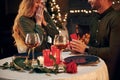 Man proposing a beautiful woman to marry him in an elegant restaurant. Young lovely couple have romantic dinner indoors together Royalty Free Stock Photo