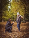 Man Proposing marriage to girlfriend on one knee in autumn park.