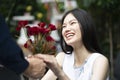 A man is proposing marriage to a smiling woman with a lovely flower bouquet in a beautiful garden Royalty Free Stock Photo