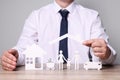 Man protecting figures of family, car and house at wooden table. closeup. Insurance concept Royalty Free Stock Photo