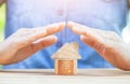 Man protecting house model on table. planning savings money of coins to buy a home Royalty Free Stock Photo