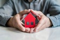 Man protecting red house model with a roof. Male hands covering small home. Insurance concept . Royalty Free Stock Photo