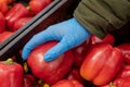 Man in protective blue gloves buys vegetables. Close-up. Red pepper in hand. Buying food during a pandemic
