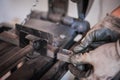 The man with protective gloves holds the cut metal after grinding