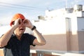 Man in a protective helmet holds his hands in the form of binoculars looks into the distance standing on the roof of a building Royalty Free Stock Photo