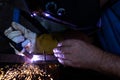 A man with protective helmet welding two pieces of metal. Sparks