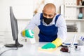 Man in protective mask and in an overalls cleans the table Royalty Free Stock Photo