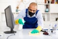 Man in protective mask and in an overalls cleans the table Royalty Free Stock Photo