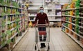 Man in protective mask shopping in supermarket pushing trolley during epidemic