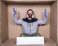 Man in a protective mask sits at a cardboard box, showing his helplessness