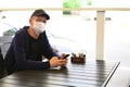 Man in protective mask sitting in empty cafe