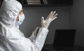 Man in protective suit and medical mask is wears rubber gloves at his working place at home during quarantine. Designer Royalty Free Stock Photo