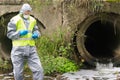 A man in a protective suit takes soil samples into a Petri dish from the sewage treatment plant Royalty Free Stock Photo