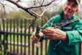 Man pruning tree with clippers. Male farmer cuts branches in spring garden with pruning shears or secateurs Royalty Free Stock Photo