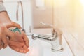 A man in a public place washes his hands in the sink. Squeezing antibacterial hand soap. Precautions and protection for