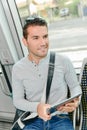 man on public transport holding tablet