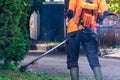 Man public worker tidy up the city street yard with the grass cutter or trimmer machine with a smoke blow away