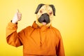 Man with pug dog mask isolated on a yellow background. Man gesture with approval sign, good deed