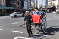 Man pulling a rickshaw with two passengers on the streets of Tokyo, Japan