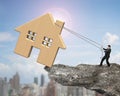 Man pulling rope to move wooden house on cliff edge Royalty Free Stock Photo