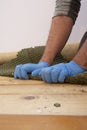 Man pulling up and removing carpet underlay from a wooden floor.