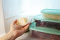 A man pulls frozen vegetables out of the freezer. A man takes corn from the fridge. Plastic containers with frozen meat,