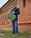 A man pulls a grey laptop out of his backpack. Universal city sports bag in khaki color. A man`s hand folds a laptop into a bag.