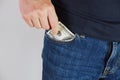 The man pulls money out of the pocket of blue jeans. Close-up view of the hands. Place for your text Royalty Free Stock Photo