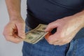 The man pulls money out of the pocket of blue jeans. Close-up view of the hands. Place for your text Royalty Free Stock Photo