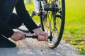 Man pumping bicycle wheel in the park. Man inflates bicycle wheel using a pump. Pumping air into an empty wheel of bike. Royalty Free Stock Photo