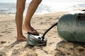 Man pumping inflatable rubber fishing boat at sandy beach on sunny day, closeup Royalty Free Stock Photo