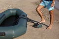 Man pumping inflatable rubber fishing boat at sandy beach on sunny day, closeup Royalty Free Stock Photo