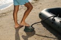 Man pumping inflatable rubber fishing boat at sandy beach on sunny day, closeup Royalty Free Stock Photo