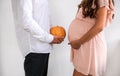 Man with pumpkin opposite a pregnant woman. Royalty Free Stock Photo