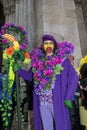 Man in purple costume holding a stick of fruit in Easter Bonnet Parade