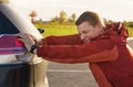 A man pushes his broken car to a parking lot. Royalty Free Stock Photo