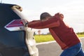 A man pushes his broken car to a parking lot. Royalty Free Stock Photo