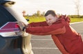 A man pushes his broken car to a parking lot. Royalty Free Stock Photo