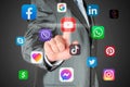 Man pushes virtual social media app icon on dark background, connection to social media concept Royalty Free Stock Photo