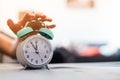 Man is pushing an alarm clock in the morning, sunshine and blurry background