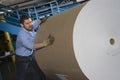 Man Pushing Huge Roll Of Paper In Factory