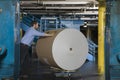 Man Pushing Huge Roll Of Paper In Factory