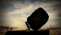 Man Pushing a large Rock At Sunset. Hard work and Heavy task Concept. The person rolls The Stone on mountain