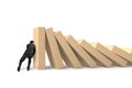 Man pushing and stopping dominoes falling Royalty Free Stock Photo